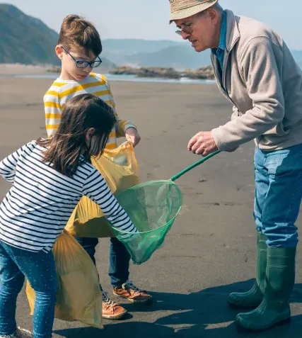 A group of volunteers collecting litter on a sandy beach during a cleanup event.